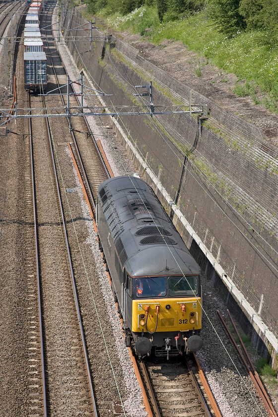 56312, 12.11 Barrow Hill-Willesden LE (0Z57), Roade cutting 
 Despite having a relatively high number 56312 'Jeremiah Dixon' is in fact the earliest and oldest survivor of the once one hundred and thirty-five strong class of locomotives. As a young spotter back in 1977 the 56s were viewed as being very modern and hi-tech (that they were of course!) and as a portent of things to come, the first thirty were manufactured abroad, in this case in Romania. Today, some thirty-seven years later it is remarkable that a number of these locomotives are still in use on the national network. Now operated by DCR the veteran diesel passes through Roade cutting as the 0Z57 12.11 Barrow Hill to Willesden light engine. Notice that I was almost bowled by the 4M20 Freightliner hence the rather head-on and portrait composition! 
 Keywords: 56312 12.11 Barrow Hill-Willesden light engine 0Z57 Roade cutting Jeremiah Dixon