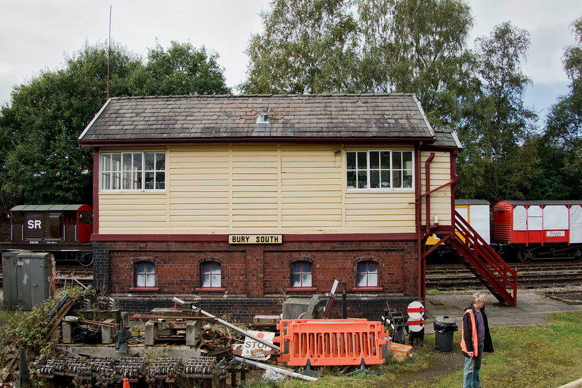 Bury South signal box (L&Y, 1910) 
 The rear of Bury's South signal box is seen from the passing train complete with a collection of S & T equipment scattered about on the ground. This is the original 1910 Lancashire and Yorkshire box in its as-built location that was closed by BR in 1980. The ELR re-opened the box in 2004 with a hybrid frame created from Wigan S & T store (fifty levers) and Hadfield (fifteen levers). The box controls all the sidings and lines to the south of Bury station and access to the line that leads up to the heritage line's convergence with NR metals at Hopwood ground frame. 
 Keywords: Bury South signal box