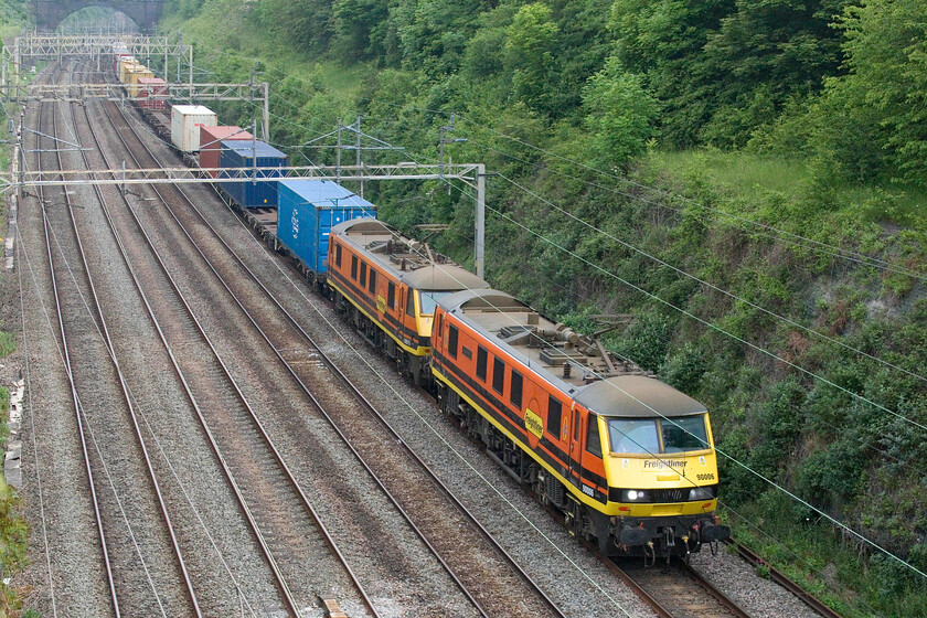 90006 & 90015, 03.14 Garston-Felixstowe North (4L97, 18E), Hyde Road bridge 
 Freightliner's 90006 leads 90015 through Roade cutting taken from the village's Hyde Road bridge working the daily 03.14 Garston to Felixstowe North 4L97 service. Up until a few years ago, this service was in the hands of the venerable Class 86s before their withdrawal. But now it is the far newer Class 90s which are being withdrawn whittling the class down to less than half of what they were. Admittedly, the majority of these scrap locomotives have been in store in various states of disrepair for many years pending a decision on their future. 
 Keywords: 90006 90015 03.14 Garston-Felixstowe North 4L97 Hyde Road bridge Freightliner