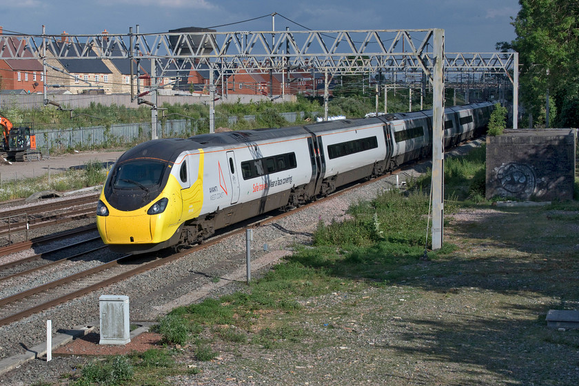 390042, VT 17.30 London Euston-Glasgow Central (1S90, 1L), site of Roade station 
 On the day that the wearing of face protection became mandatory on public transport, Avanti West Coast's 390042 enters into the spirit sporting its own mask and bearing the message 'Safe Travels (sic). Wear a face covering'. The Pendolino is seen passing Roade working the 17.30 Euston to Glasgow Central 1S90 under a very threatening sky. This Pendolino is one of two that have been adorned with the vinyls and the message - the other one being 390122 'Penny the Pendolino'. 
 Keywords: 390042 17.30 London Euston-Glasgow Central 1S90 site of Roade station Avanti West Coast Pendolino Face mask Pandemic COVID-19