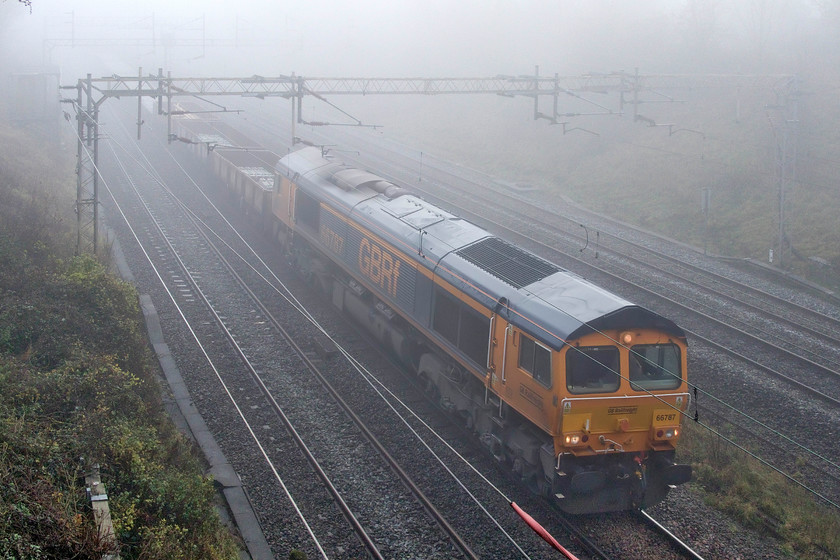 66787, 10.23 Watford South Junction-Bescot (6G51, 7L), Victoria bridge 
 66787 emerges from the gloom at Victoria bridge between Roade and Ashton leading the 6G51 10.23 Watford South to Bescot engineering train. The wagons contained used concrete sleepers and plenty of used ballast all going for recycling. 
 Keywords: 66787 10.23 Watford South Junction-Bescot 6G51 Victoria bridge GBRf