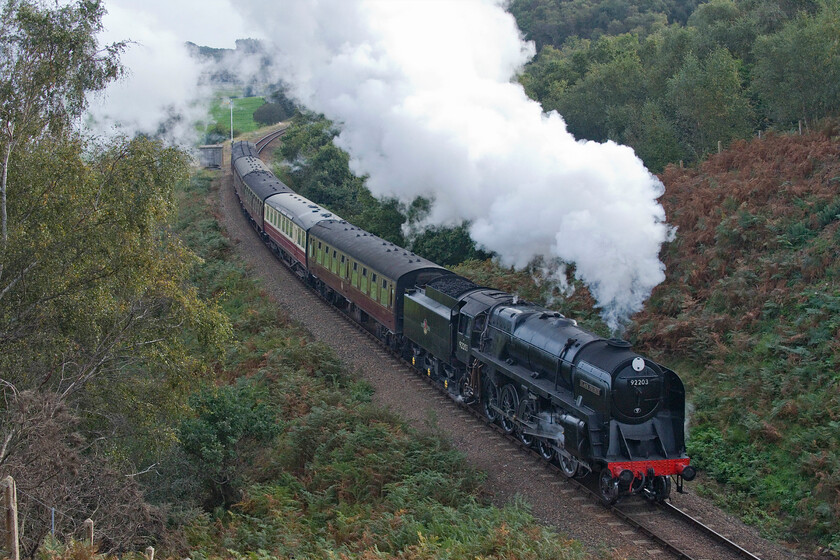 92203, 10.15 Sheringham-Holt, Kelling bank-18.10.23 
 With its 39,701lbf tractive effort, a 9F will have no difficulty lifting six coaches from a standing start at Weybourne up Kelling bank on the North Norfolk Railway. Long-term resident 92203 'Black Prince' is seen leading the 10.15 Sheringham to Holt service, the first steam-hauled service of the day. As well as their power and ability to haul both fast express passenger trains and heavy freight the 9F's were renowned for their excellent fuel consumption making them arguably the finest production steam engines ever built; such a shame that some saw just five years of service with British Railways. 
 Keywords: 92203 10.15 Sheringham-Holt, Kelling bank 9F Black Prince