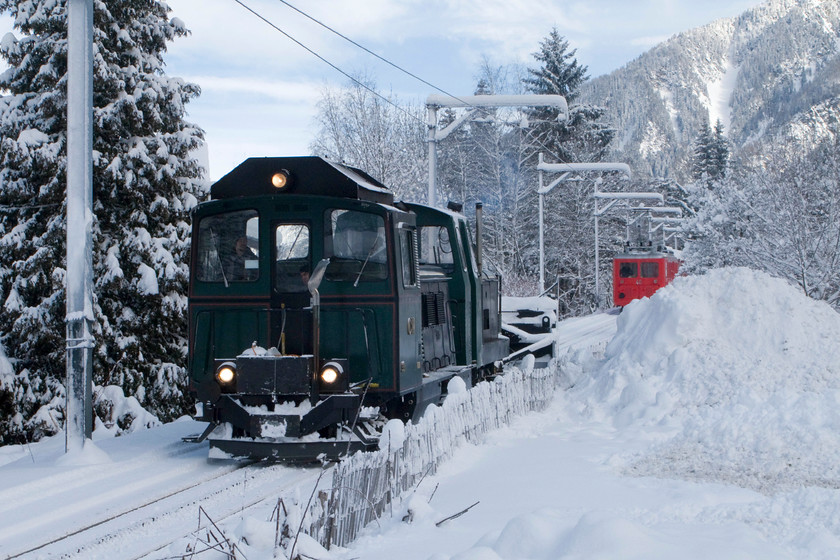 33, snow-clearing train, Chamonix Montenvers Mer de Glace line, Chemin du Pied-du Grepon foot crossing 
 Having cleared the line of snow earlier in the morning, diesel-powered number 33 and its un-numbered cousin, descend the Montenvers railway with extreme caution. Just behind the snow-clearing train are cabins 46 and 62 taking electric power from the overhead live wires. The carriages had been released from the upper station at Montenvers Mer de Glace by the snow clearing operations and would hopefully be in passenger use later on on this day. 
 Keywords: 33 snow-clearing train Chamonix Montenvers Mer de Glace line Chemin du Pied-du Grepon foot crossing