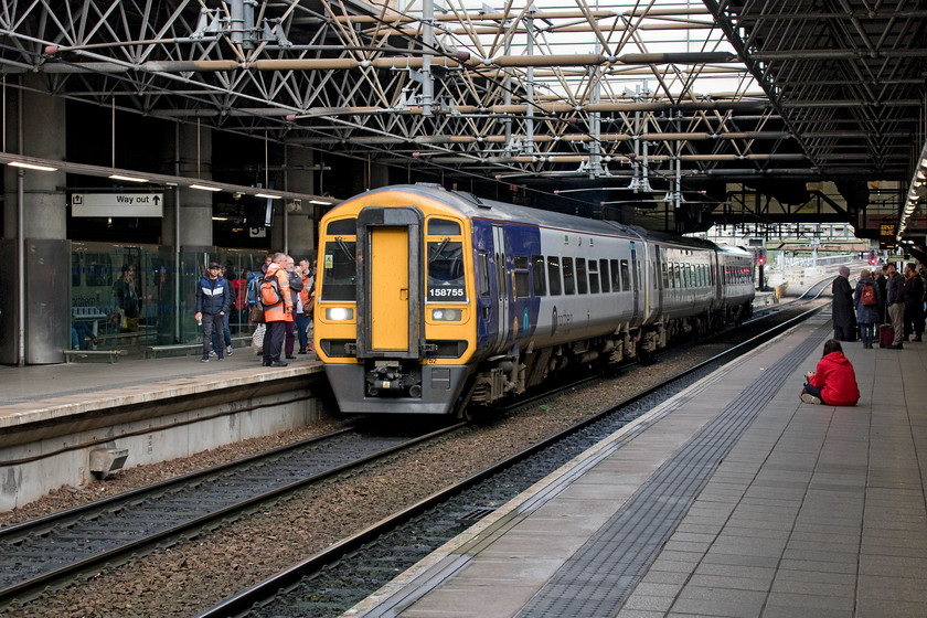 158755, NT 15.48 Rochdale-Clitheroe (2N51, 1E), Manchester Victoria station 
 158755 has just arrived at the bi-directional platform four with the 15.48 Rochdale to Clitheroe with a crew change about to take place. On leaving Victoria it will head for Bolton and via the single-track Darwen route to Blackburn. From Blackburn, it will proceed toward Hellifield as far as its termination at Clitheroe. Notice the young person sitting on platform three. Just after I took this picture two members of the BTP came over and asked her to move and not to sit on the platform. Whilst it is not what you and I may do, I can't see a reason to ask her to move but perhaps in my nativity, perhaps I'm missing something? 
 Keywords: 158755 15.48 Rochdale-Clitheroe 2N51 Manchester Victoria station