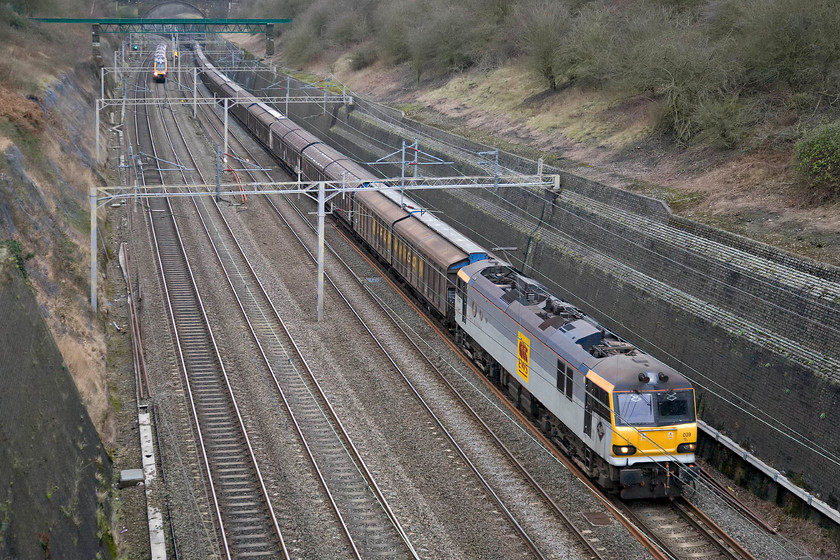 92039, 14.05 DIRFT-Dollands Moor (6O67), Roade cutting 
 FREIGHT NUMBER THREE - A seven day a week working is the return of empty Ferrywagons from Daventry to Dollands Moor for return to the continent via the Channel Tunnel. Running as 6O67 92039 'Johann Strauss' in its two-tone Railfreight grey with full height EWS logo vinyls leads the train through Roade cutting as a Virgin Voyager approaches at speed on the up fast. 
 Keywords: 92039 14.05 DIRFT-Dollands Moor 6O67 Roade cutting EWS Ferrywagons Johann Strauss