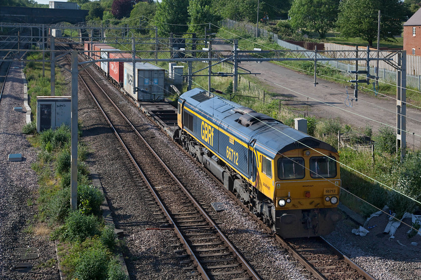 66712, 14.18 Trafford Park-Felixstowe North (4L18, 7E), site of Roade station 
 66712 'Peterborough Power Signalbox' bursts into the superb evening sunshine leading the 4L18 14.18 Trafford Park to Felixstowe Freightliner. This locomotive is another of GBRf's stock that is maintained to high standards with smart paintwork. It is also noticeable that their shade of yellow always appears to have a slightly more orange hue than normal. 
 Keywords: 66712 14.18 Trafford Park-Felixstowe North 4L18 site of Roade station GBRf Peterborough Power Signalbox