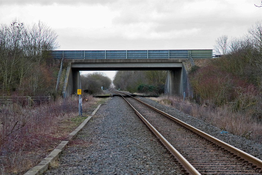 Trackbed looking NE prior to upgrading, Wendlebury SP561182 
 The scene here at Wendlebury is set to change massively over the coming few years as the line between, initially at least, Bicester and Oxford is upgraded to a double track one hundred miles per hour route as the initial phase of the east to west rail link. For the moment, it remains a single track with sixty miles per hour working and numerous farm and foot crossings. The large bridge that dominates this view carries the M40 motorway over the line. Incidentally, the twenty-two and a quarter mile post is the distance from the line's junction with the WCML at Bletchley. 
 Keywords: Trackbed looking NE prior to upgrading Wendlebury SP561182