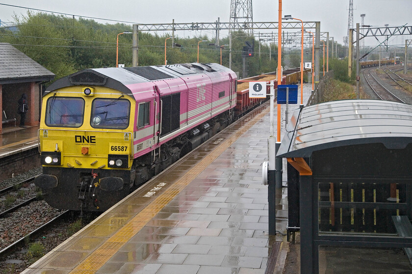 66587, 66593, 09.14 Bescot Yard-Bromford Bridge (6Y60, 30L), Bescot Stadium station 
 Having arrived nearly an hour late, along with three other Class 66s, a little earlier, 66587 'As One We Can' leads the 09.14 Bescot Yard to Bromford Bridge engineering train, also late. Through the pouring rain, 66593 '3MG Mersey Multimodal Gateway' can be seen at the rear of the train. 
 Keywords: 66587 66593 09.14 Bescot Yard-Bromford Bridge 6Y60 Bescot Stadium station As One We Can 3MG Mersey Multimodal Gateway