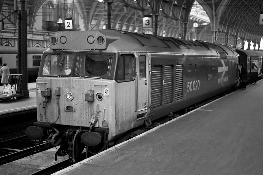 50020, 11.22 Liverpool Lime Street-London Paddington (1V41), London Paddington station 
 A throwback from GWR days was when one could get a direct service train all the way from Merseyside to Paddington that has now disappeared from our railways. 50020 'Revenge' has just arrived with the 1V41 11.22 from Liverpool Lime Street that it hauled from Birmingham New Street with AC power to there. Considering that 50020 had only returned to traffic after its refurbishment and repaint into 'large-logo' livery exactly two months to the day previously it is already beginning to look a little work-weary! Unfortunately, BR did not always take a great deal of care maintaining the external appearance of their locomotives, ironically exacerbated by putting them too frequently through the washer that contained too much caustic cleaning agent causing chronic paint fade. 
 Keywords: 50020 11.22 Liverpool Lime Street-London Paddington 1V41 London Paddington station Revenge