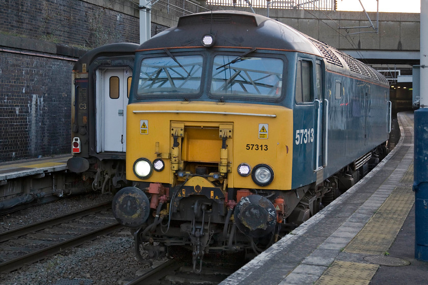 57313, London Euston-Wembly LE, London Euston station 
 Within just two minutes of the charter leaving Euston for Carlisle, 57313 has made its way up platform two at Euston ready to make its way to Wembley yard for stabling during the day. The crew were a little premature as the loco. was halted just beyond where I am standing under a red starter signal until the signalman could give it permission to continue its short journey. Notice the rear of the Lowland Caledonian Sleeper train in platform one that had arrived considerably earlier in the morning. I cannot help feel that 57313 (formally 47371) does not look quite so smart in this teal livery as it did when it was one of Virgin's dedicated Thunderbirds. 
 Keywords: 57313 London Euston-Wembly LE London Euston station light engine