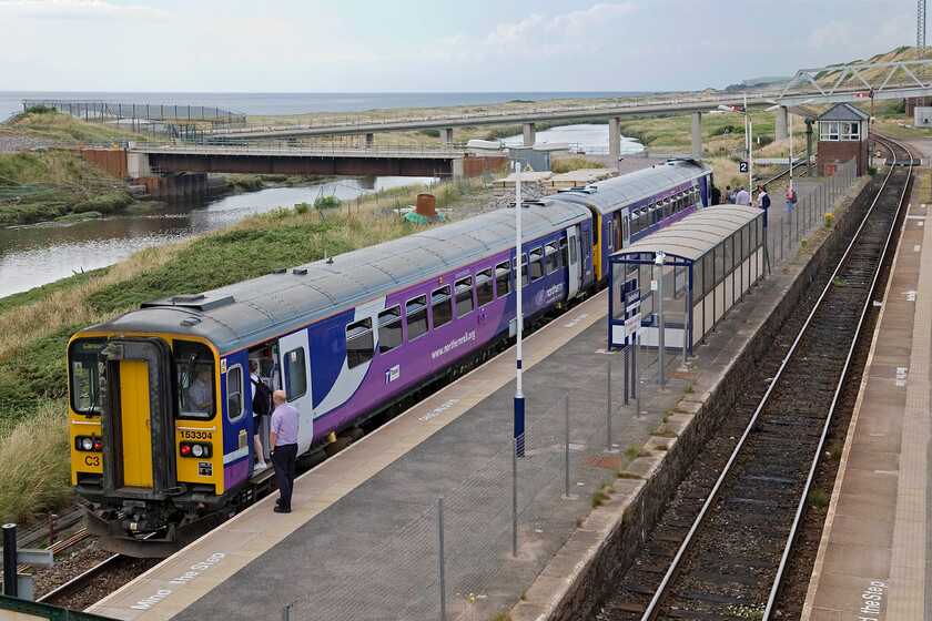 153304 & 153360, NT 13.32 Lancaster-Carlisle, Sellafield station 
 The last few passengers squeeze on board the 13.32 Lancaster to Carlisle service at Sellafield station. With Northern knowing the shift changes at the huge reprocessing plant one might have thought that they might have strengthened certain trains beyond just coupling 153304 and 153360 together? This is an interesting photograph that seems to play tricks on the eye. Looking slightly downwards and with various horizontals it appears, looking at the train, that I have tipped the camera slightly. However, using the ultimate datum point of the sea in the background indicates that it is level on the horizontal. 
 Keywords: 153304 153360 13.32 Lancaster-Carlisle Sellafield station