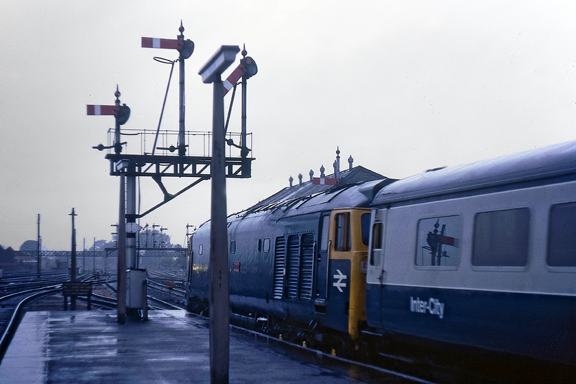 50029, 17.32 London Paddington-Penzance (1B22), Taunton station 
 I am having to stand under the end of the platform canopy in order to shelter from the torrential rain falling at Taunton, I suspect that the open droplight of the leading coach will allow in a fair bit of water! 50029 'Renown' is getting the 17.32 Paddington to Penzance underway beneath a sea of semaphore signals. The West signal box, that controls them, can be seen just behind rising above the roof of 50029. Notice the bright reflection on the cab side of 'Renown', I am not at all sure what this is, could it just be the setting sun appearing behind the black clouds that fill the sky? 
 Keywords: 50029 17.32 London Paddington-Penzance 1B22 Taunton station