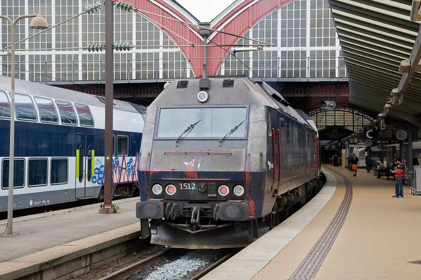 1512, 13.58 Kalundborg-sterport, Copenhagen Central station 
 Looking distinctly battle-weary DSB Class ME number 1512 waits at the rear of the 13.58 Kalundborg to sterport. The train is seen just outside the grand train shed of Copenhagen Central station. Yet another graffiti daubed double-decker coach is seen to the left of the sterport service. 
 Keywords: 1512 13.58 Kalundborg-sterport Copenhagen Central station