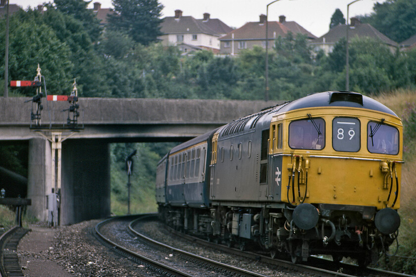 33119, 10.10 Portsmouth Harbour-Bristol Temple Meads (1V24), west of Salisbury tunnel 
 This is one time when the two-character headcode that the Southern Region of BR still used (officially or unofficially, I am not too sure?) enabled me to discover and correct my initial identification using the wonders of the internet. Back in 1981 using just the working timetable I had this service down as a Waterloo to Salisbury semi-fast service. But, wearing an 89 headcode would suggest something else. Indeed, it has subsequently been established that it was actually the 10.10 Portsmouth Harbour to Bristol Temple Meads service. It is seen passing Salisbury Tunnel Junction's up home bracket signal at a spot some distance west of the junction with a short tunnel between it and the junction itself with 33119 leading. Notice the soon-to-be-commissioned colour light on the other side of the bridge that would replace the bracket signal. Incidentally, this particular locomotive was the prototype of the 33/1 sub-class built for push-pull working with 4TC EMUs and the only one to ever wear a green livery (except for any others subsequently repainted). 
 Keywords: 33119 10.10 Portsmouth Harbour-Bristol Temple Meads 1V24 west of Salisbury tunnel Crompton.