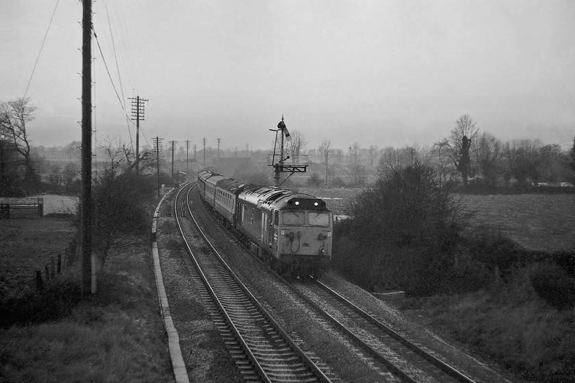 50003, 13.48 Plymouth-London Paddington (1A03), Lavington ST987546 
 This picture amply illustrates how good Ilford FP4 film was (and still is as it can be bought today). Despite being only 125ASA it has handled the very low light conditions here at Lavington. There is virtually no grain on the negative (today it would be called 'noise') and a very atmospheric picture has been produced. 50003 'Temeraire' is seen working past Lavington's up bracket that now only has the up main home arm in place. It is leading the 1A03 13.48 Plymouth to Paddington train; can anybody help with the reporting number? It is fitting that this lovely image ends this trip as all the boxes and semaphore here and at Woodborough would come out of use the following Saturday as the next phase of the Reading PSB MAS signaling was switched on. 
 Keywords: 50003 13.48 Plymouth-London Paddington 1A03 Lavington ST987546