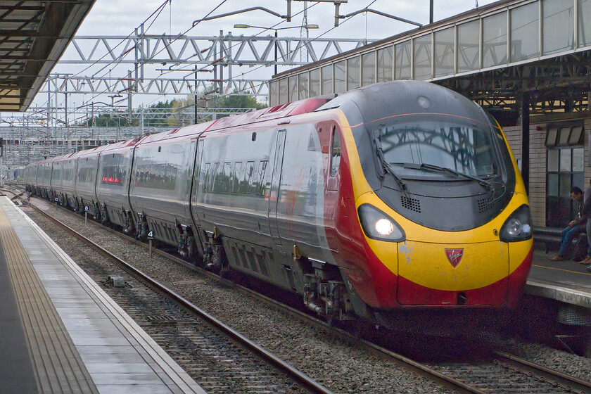 Class 390, VT 09.50 Birmingham New Street-London Euston (1B12), Milton Keynes station 
 An unidentified Class 390 Pendolino passes through Milton Keynes at full line speed working the 09.50 Birmingham New Street to Euston service. It is interesting to note that whilst the subject is pretty much pin sharp the refelection in the Pendolino's screen of the stanchion is shwing some significant blurring. 
 Keywords: Class 390 Pendolino 09.50 Birmingham New Street-London Euston 1B12 Milton Keynes station