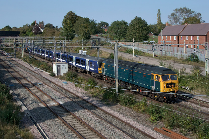 47727, 360113 & 47739, 11.52 Ilford EMUD-Northampton EMD (5Q60, 13L), site of Roade station 
 47727 'Edinburgh Castle/Caisteal Dhun Eideann' brings up the rear of the 11.52 Iford to Northampton EMU depot (Kingsheath) 5Q60 drag with 360113 in front. Almost hidden from view is 47727 at the front of the train that has become a regular Sunday working through the summer. The Class 360 Desiros are being taken to Kingsheath for modifications prior to their moving to the MML, whenever that may happen? I have asked the question but not had a credible answer, why can't these units run from Ilford to Northampton (and back again) under their own power rather than having to be dragged by a pair of thirsty diesels with no doubt at great expense? 
 Keywords: 47727 360113 47739 11.52 Ilford EMUD-Northampton EMD 5Q60 site of Roade station Edinburgh Castle Caisteal Dhun Eideann GBRf