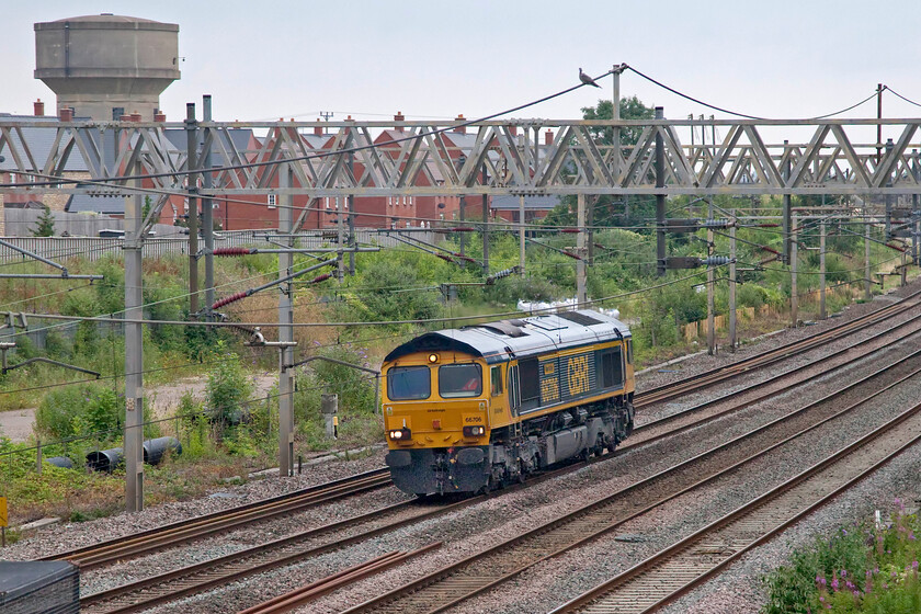 66706, 15.04 Tonbridge West Yard-Bescot (0M69, 4E), site of Road station 
 A very ordinary photograph in particularly poor lighting for the last week in July shows 66706 'Nene Valley' passing the site of Roade station with one of the village's two water towers dominating the scene. The Class 66 was running as 0M69, the 15.04 Tonbridge West to Bescot that was supposed to have been conveying a brand new 69001 'Mayflower' (formally 56031). Unfortunately, something went wrong with just GBRf's 66 returning to Bescot on its own passing here exactly on time. The wait for me to see a Class 69 continues......! 
 Keywords: 66706 15.04 Tonbridge West Yard-Bescot 0M69 site of Road station GBRf Nene Valley