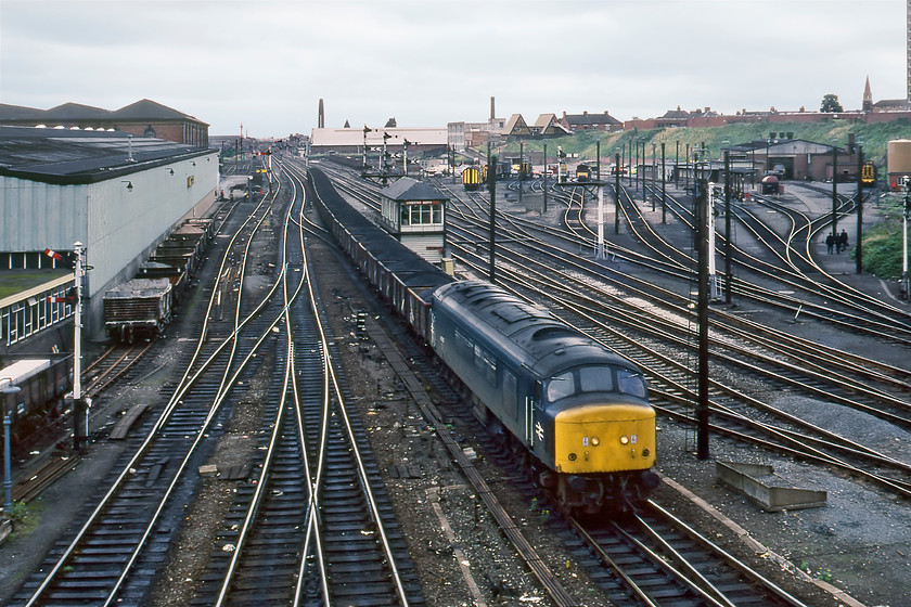 45057, up coal train, Leicester North 
 A superb scene taken from Leicester's Sparkenhoe Road bridge sees 45057 bring a train of loaded coal wagons slowly towards the station from the north. Peak 45057 is an interesting member of the class as it had different nose cone types. The end facing the camera here is the twin marker light type that had replaced a single headcode panel. However, at the other end facing the coal wagons, it had split headcode boxes that it kept, I believe until its demise in January 1985 returning here to Leicester to be cut up at Vic Berry's scrapyard just south of the station. In the background is Leicester North signal box and beyond the diesel depot (LR). After being downgraded to carriage stabling it is now home to the fast-growing rail procurement company UKRL. All of the buildings to the left have now been demolished and have given way to a variety of retailing establishments on the St. George's retail park. 
 Keywords: 45057 up coal train Leicester North Sparkenhoe Road