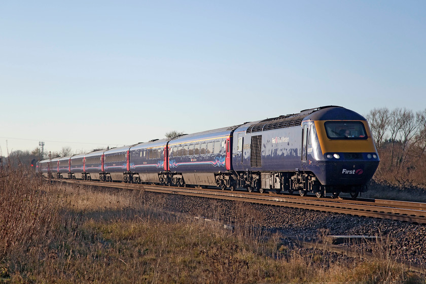 43139 & 43023, GW 12.55 Cardiff Central-London Paddington (1L60), South Marston foot crossing SU196870 
 Catching the late afternoon sun 43139 'Driver Stan Martin 25 June 1950 - 6 November 2004' leads the 12.25 Cardiff Central to Paddington service with 43023 at the rear. Apart from the painting of some of the sets and power cars into their retro. green livery, this First Group livery is likely to be the final incarnation of the HSTs on the GWML before their withdrawal sometime over the coming eighteen months or so. There is absolutely no evidence of the forthcoming electrification at this location, a foot crossing over the line at South Marston near Swindon. Directly behind the train and the trees is the huge Honda car factory that remains rail connected but not served. 
 Keywords: 43139 43023 12.55 Cardiff Central-London Paddington 1L60 South Marston foot crossing SU196870