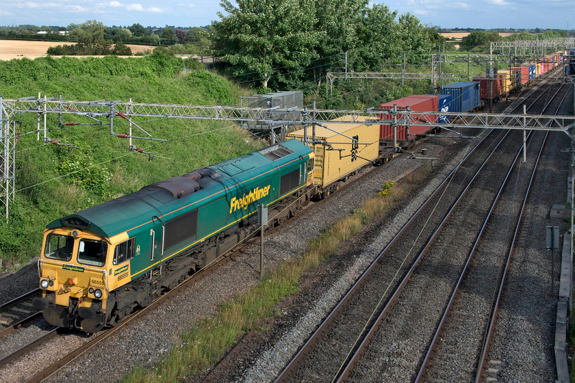 66555, 12.57 London Gateway-Garston (4M57, 38E), Victoria bridge 
 At last, the sun comes out as a train is passing! Looking so much better for some summer rays, 66555 heads north down the WCML between Roade and Ashton leading the 4M57 12.57 London Gateway to Garston Freightliner. Despite appearances suggesting that the train was well loaded, the whole of the rear half was just empty flats indicating that international trade is still very slow as the effects of the COVID-19 pandemic still bites hard. 
 Keywords: 66555 12.57 London Gateway-Garston 4M57 Victoria bridge Freightliner