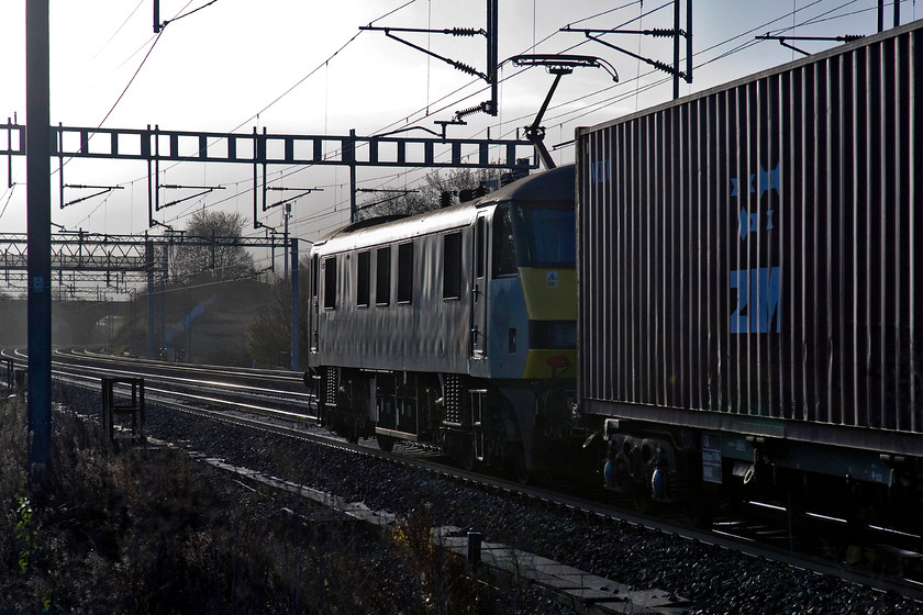 Class 90, 04.57 Trafford Park-Felixstowe North (4L97), Ashton Road bridge 
 The 04.57 Trafford Park to Felixstowe 4L97 Freightliner heads south between Roade and Ashton on the WCML with an unidentified Class 90 leading. I like the dramatic lighting in this photograph from the angry sky to the sun glinting off the side and roof of the Class 90. 
 Keywords: Class 90 04.57 Trafford Park-Felixstowe North 4L97 Ashton Road bridge Freightliner