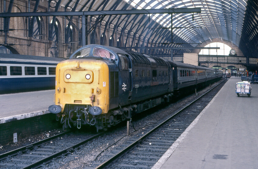 55004, 16.05 London King's Cross-York (1L44), London King's Cross station 
 With the station clock reading 15.50 55004 'Queen's Own Highlander' and its train is being prepared to leave in fifteen minutes with the 16.05 semi-fast service to York composed of six air conditioned Mk. IIs and what I assume to be a Mk. 1 buffet or restaurant car marshalled towards the middle. With a haze of diesel fumes appearing to be coming from just one of the exhausts, it would appear that 55004 will be hauling the train with just 1,650hp on tap on one engine. This was a very common occurrence in the last years of Deltic operation to keep these fine machines in service by helping to reduce engine hours and thus preserving the number of 'spare' units available to be swapped over at 'the Plant' in Doncaster. This would be ample power for this train to maintain its tight timings on this late afternoon commuter service to York. 
 Keywords: 55004 16.05 London King's Cross-York 1L44 London King's Cross station Deltic Queen's Own Highlander