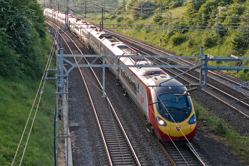 Class 390, VT 17.55 Manchester Piccadilly-London Euston (1A61), having been held at signal, Victoria bridge 
 Catching some evening sunshine an unidentified Class 390 Pendolino, working the 17.55 Manchester to Euston service passes Victoria bridge near Roade. However, looks can be deceiving as rather than travelling at line speed the Pendolino is actually moving at walking pace. All services had been stopped for some time linked, I suspect, to some sort of signalling failure. 
 Keywords: Class 390 17.55 Manchester Piccadilly-London Euston 1A61 having been held at signal, Victoria bridge VWC Virgin Pendolino