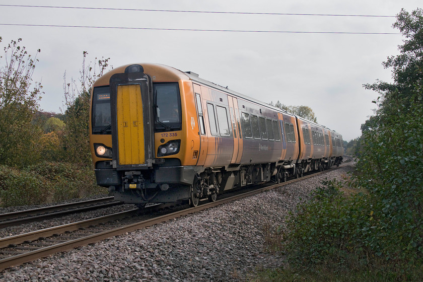 172335, LN 13.09 Dorridge-Kidderminster (2K37, 7L), Widney Manor station 
 172335 has just left its start point at Dorridge a couple of miles south of where I am standing in Widney Manor station's car park. The unit is working the 13.09 Dorridge to Kidderminster service that is slowing for its stop at Widney Manor station just behind me. Whilst this scene looks rural and quiet the incessant noise from the M42 motorway did spoil things. It passes under the line from left to right just beyond the rear of the train. 
 Keywords: 172335 13.09 Dorridge-Kidderminster 2K37 Widney Manor station