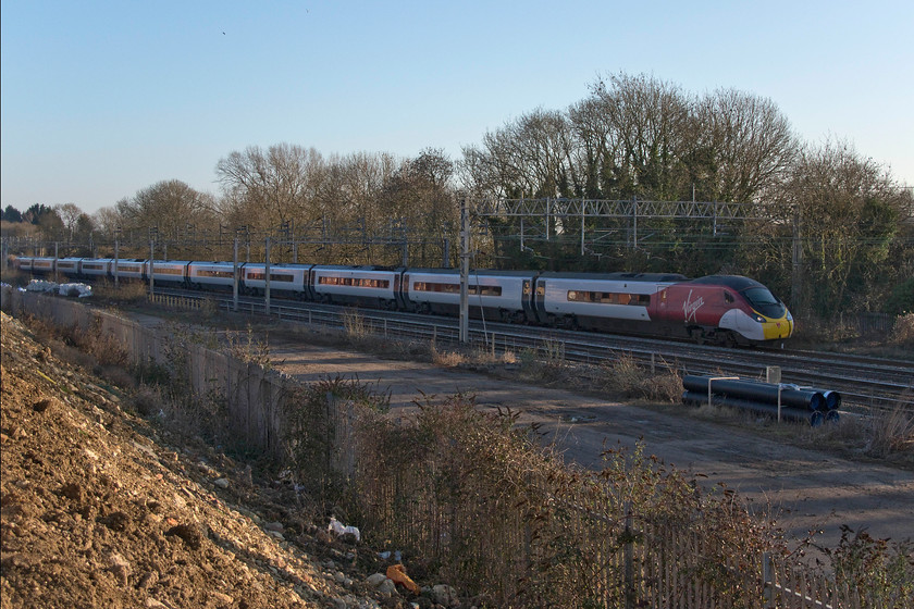 390115, VT 15.37 London Euston-Manchester Piccadilly (1H70, 1E), Pianoforte site, Roade 
 This is a spot that has been afforded by the demolition of Roade's old Pianoforte site and the building of the new housing estate on its land. Unfortunately, I am the wrong side for the afternoon sun but I am not sure if I am going to able to get access in the future? 390115 heads north with the 15.37 Euston to manchester Piccadilly. The empty space down below is where the once extensive sidings were located that linked the Pianoforte factory to the network. This was particularly important during the second world war when the factory was involved in the manufacturing of armaments. 
 Keywords: 390115 15.37 London Euston-Manchester Piccadilly 1H70 Pianoforte site Roade