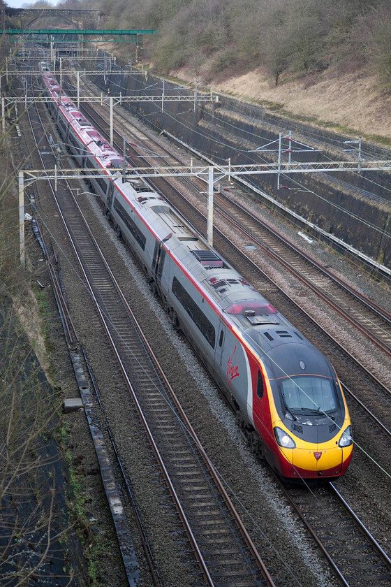 390153, VT 11.55 Manchester Piccadilly-London Euston (1A23, 6E), Roade Cutting 
 With a last 'hoorah' of sun just being picked up on its front end, 390153 'Mission Accomplished' passes through Roade Cutting working the 1A23 11.55 Manchester to London Euston. I expect that the New Year's Eve revellers on-board would have appreciated its six minute early arrival into London! 
 Keywords: 390153 11.55 Manchester Piccadilly-London Euston 1A23 Roade Cutting