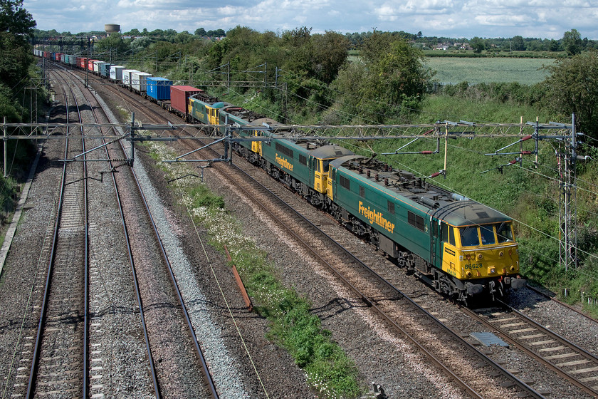 86628, 86639, 86614 & 86637, 12.30 Crewe Basford Hall-Wembley-Reception (4A96, 21E), Victoria bridge 
 This was a little unexpected! I was waiting for the 12.30 Crewe Basford Hall to Wembley 4A96 Freightliner half expecting it to be Class 86 hauled as is often the case but when this came into view I was delighted! I am not sure if two of the four locomotives made up of 86628, 86639, 86614 and 86637 had failed or if this was some sort of positioning move - advice anybody? Only the first two were taking power and it was running early after leaving Basford Hall on time. On a hot and humid afternoon, the impressive train is seen heading south with the village of Roade in the background including my house! 
 Keywords: 86628 86639 86614 86637 12.30 Crewe Basford Hall-Wembley Reception 4A96 Victoria bridge Cans AL6 Freightliner