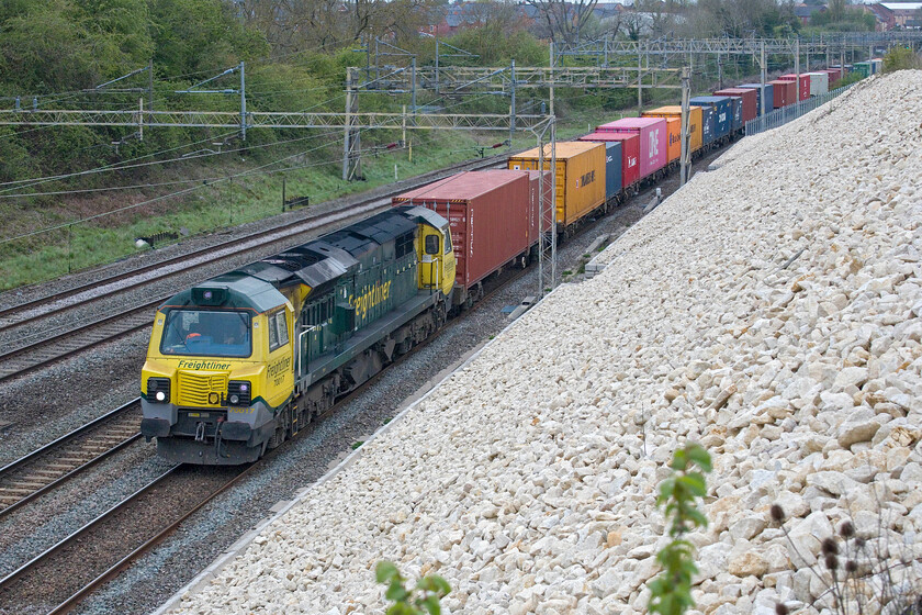 70017, 09.55 Crewe Basford Hall-Southampton MCT (4O35, 50E), Ashton Road bridge 
 The diverted 4O35 09.55 Crewe Basford Hall to Southampton Freightliner service passes Ashton Road bridge just south of Roade. The closure of the GW route between Oxford and Didcot due to repairs to the abutment of Nuneham viaduct has brought many new if temporary flows to the already busy WCML and a significant number of Class 70s. 70017 is hauling this train making its usual row shattering the quiet Northamptonshire countryside! 
 Keywords: 70017 09.55 Crewe Basford Hall-Southampton MCT 4O35 Ashton Road bridge Freightliner