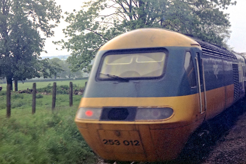 253012, stabled, Bathampton loop 
 A grab shot that gets no marks for its technical aspects or for its composition! However, it's a bit of a rarity so I have included it. It was taken from the droplight of the train that I was on travelling from Bath Spa to Bradford-on-Avon. As we approached Bathampton Junction I became aware of an HST in the up loop. This event was prompted because of the closure of the GWML due to an earth slip at Christian Malford between Chippenham and Swindon. BR put an emergency timetable in place so Bath passengers were not left stranded. HSTs worked to and from Paddington via the South Wales route from Swindon heading south to Bristol and Weston-Super-Mare from Stoke Gifford Junction. Some services were reversed at Temple Meads and then headed the short distance to Bath. After the passengers disembarked, the train ran ECS to Bathampton Junction for a short layover in the loop. They then returned to Bath, picked up passengers, proceeded to Bristol and then reversed again for the journey back to Paddington via the South Wales route again. Here, set 253012 is seen in the loop ready to form what is believed to be the 18.25 Bath-London Paddington (via Bristol Temple Meads (reversal) and Bristol Parkway). Thanks to Kevin Daniel for providing this information. 
 Keywords: 253012 Bathampton loop HST