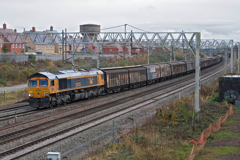 66723, 07.46 Dollands Moor-DIRFT (6M45, 7L), site of Roade station 
 GBRf's 66723 'Chinook' leads a very long 6M45 'water train' past the site of Roade station. This is a seven-day-a-week working that comes straight through the tunnel to Dollands Moor carrying thousands of bottles of European mineral water. It ends up at Daventry's rail freight terminal for UK-wide distribution. As usual, GBRf's smart presentation of their locomotives is in stark contrast to the tatty and heavily graffitied Cargowagons 
 Keywords: 66723 07.46 Dollands Moor-DIRFT 6M45 site of Roade station water train 'Chinook'