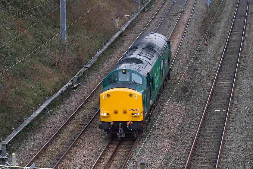 37608, 10.00 Bicester MoD-Derby RTC (0M57, 17E), Hyde Road bridge 
 The second RoG Class 37 light engine within two hours passes north through Roade on this Christmas Eve afternoon. Running as 0M57 37608 'Andromeda' is seen working the 1.00 Bicester MoD to Derby RTC that is taking a particularly circuitous route that initially saw it heading south to Oxford and Didcot and then to London. Having traversed the North London line it then took the WCML to Nuneaton where it then reversed to head east to Leicester and finally north to Derby. 
 Keywords: 37608 10.00 Bicester MoD-Derby RTC 0M57 Hyde Road bridge ROG Rail Operations Group Andromeda