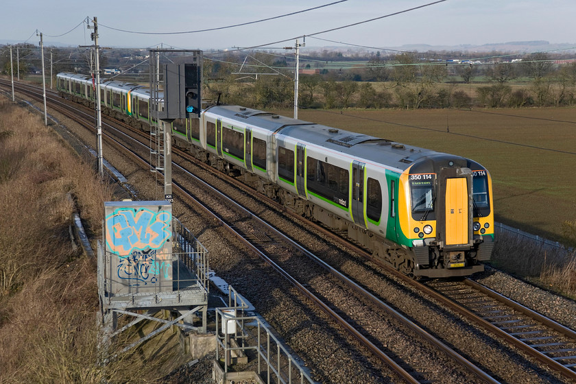 350114, LM 09.14 Birmingham New Street-London Euston (2Y01), Milton crossing 
 Desiro 350114 leads a fellow unit past Milton Crossing between Blisworth and Roade. The London Midland 09.14 Birmingham New Street to Euston service would not normally take this route via Weedon instead going through Northampton. However, the latter line was closed due to engineering works hence this service being somewhat off-route. 
 Keywords: 350114 London Midland Desiro 09.14 Birmingham New Street-London Euston 2Y01 Milton crossing