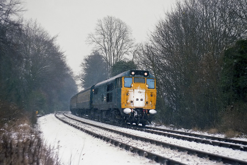 31257, 10.42 Portsmouth Harbour-Bristol Temple Meads, Turleigh Hill ST813604 
 The snow is now falling again with some intensity as 31257 leads the 10.42 Portsmouth Harbour to Bristol Temple Meads. It is pictured approximately half way between Bradford-on-Avon and Avoncliff halt. I was the wrong side of the fence taking this picture, not something that I would ever do today but there was a somewhat different attitude back in the 1970s. 
 Keywords: 31257 10.42 Portsmouth Harbour-Bristol Temple Meads Turleigh Hill ST813604