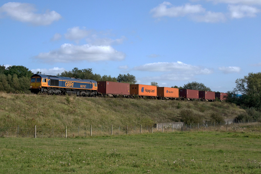 66767, 10.28 Felixstowe North-Birch Coppice (4M29, 9E), Wymondham crossing 
 In lovely warm early autumnal sunshine GBRf's 66767 heads the 10.28 Felixstowe to Birch Coppice Freightliner. The train is seen approaching Wymondham level crossing in deepest rural Leicestershire or only just at least! The county boundary with Rutland is only a short distance away following the course of the embryonic River Eye that is just off to the right in the trees. 
 Keywords: 66767, 10.28 Felixstowe North-Birch Coppice 4M29 Wymondham crossing GBRf