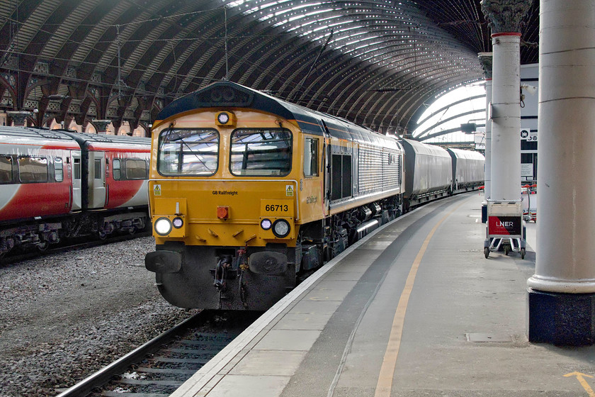 66713, 09.44 Drax-Redcar bulk terminal (4N05), York station 
 66713 'Forest City' comes to a halt at York's platform five with the 09.44 Drax power station to Redcar bulk terminal coal empties. Despite the belief that Drax has converted to biomass, this is not quite true. It still burns some coal co-firing it with biomass. Thus, there are still some regular merry-go-round style coal trains serving the huge power station with GBRF operating them. I am a little confused as to why freight trains such as this persist in coming through York station rather than using the relief lines that by-pass it to the west. This particular working was held at the down starter colour light for some time as various late-running passenger workings came in and out of the station. If there is anybody with local knowledge who can enlighten me as to why the relief lines are not used more regularly, please advise! 
 Keywords: 66713 09.44 Drax-Redcar bulk terminal 4N05 York station Forest City