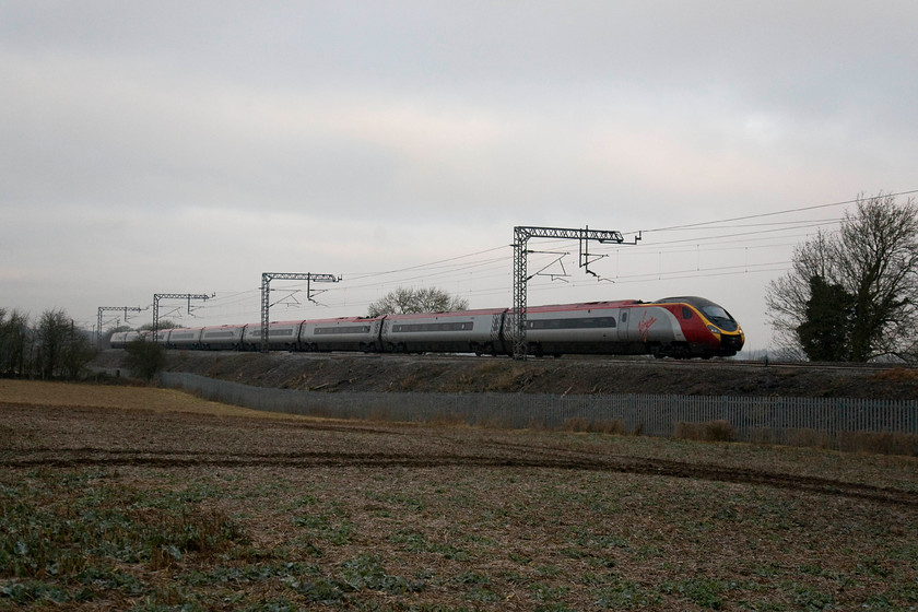 390010, VT 06.45 Wolverhampton-London Euston (1B04), Blisworth 
 With a few signs of brightness in an otherwise grey February sky, 390010 'Cumbrian Spirit' passes Blisworth working the 06.45 Wolverhampton to London Euston. Notice that the Pendolino has its nose cone cover in the retracted position, exposing its couplings and electrical systems. This is a fairly common occurrence and I do not understand, firstly why the practice persists and, secondly, how the operational systems of these complex trains are not affected by it? 
 Keywords: 390010 06.45 Wolverhampton-London Euston 1B04 Blisworth