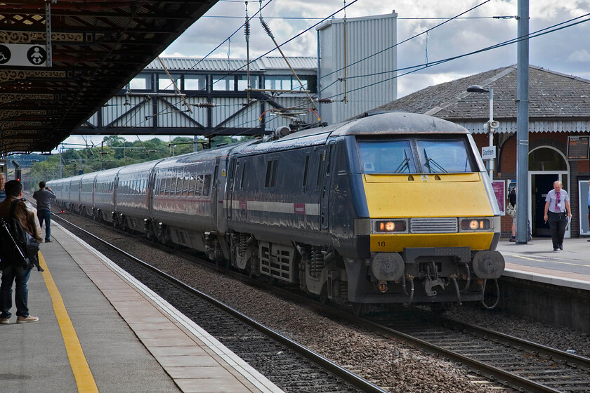 91118, GR 13.00 London King's Cross-Edinburgh Waverley (1S18), Grantham station 
 Still wearing its GNER paint 91118 slows for its stop at Grantham station working the 13.00 King's Cross to Edinburgh East Coast service. The train appears to have captured the attention of another enthusiast further along the platform who is filming its arrival on his mobile 'phone. 
 Keywords: 92118 13.00 London King's Cross-Edinburgh Waverley 1S18 Grantham station