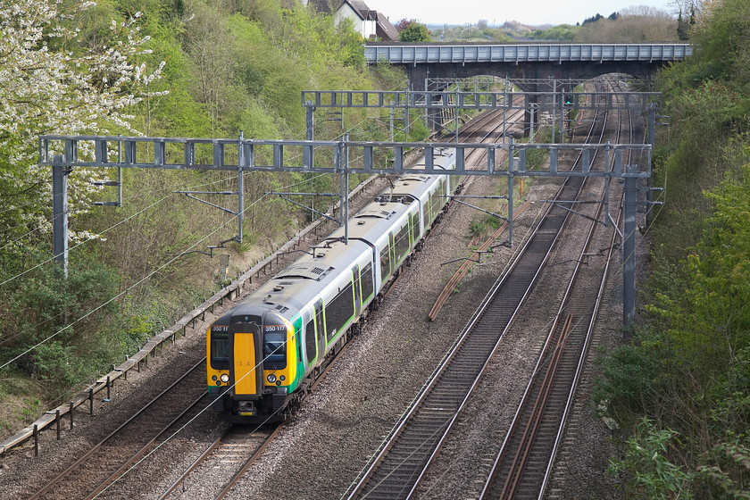 350117, LM 14.13 London Euston-Birmingham New Street (1Y45, RT), Hyde Road bridge 
 With the Blackthorn still in flower on the embankment, 350117 forms the 14.13 London Euston to Birmingham New Street. It is viewed from Hyde Road bridge in Roade, Northamptonshire. The bridge in the distance is carries the A508 over the railway and just beyond that was the site of Roade station closed in September 1964. 
 Keywords: 350117 1Y45 Hyde Road bridge