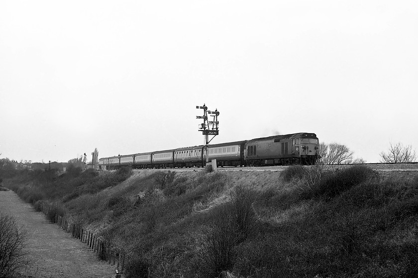 50028, 09.20 Paignton-London Paddington, Heywood Road 
 50028 'Tiger' takes the 09.20 Paignton to Paddington out of Westbury towards Heywood Road Junction. It is passing the magnificent down bracket signal controlled by the signal box some distance to the right. The lower arms to the right, indicating the subordinate route, are for the tightly curved spur that goes through to Hawkeridge Junction that enabled trains to continue through to the Avon Valley and beyond avoiding having to go into Westbury and reverse. 
 Keywords: 50028 09.20 Paignton-London Paddington Heywood Road