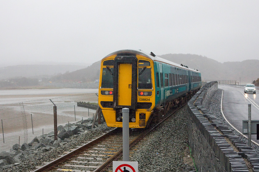 158824, AW 10.09 Birmingham International-Pwllheli (2J11), Llandecwyn station 
 Apologies for the terrible composition of this picture with the sign in the middle of the departing train but it was absolutely pouring with rain and we arrived at the station as the train was stopping. 158824 leaves the rather exposed halt of Llandecwyn with the 10.09 Birmingham International to Pwllheli. 
 Keywords: 158824 10.09 Birmingham International-Pwllheli 2J11 Llandecwyn station