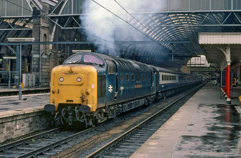 55004, 16.05 London King's Cross-York (1L44), London King's Cross station 
 With a characteristic plume of exhaust from just one of its engines 55004 'Queen's Own Highlander' gets away from King's Cross with the 1L44 16.05 to York. Close examination of the large station clock reveals that the train was leaving about a minute late but even running on one engine the Deltic would have ample power to keep the sem-fast working on time to Yorkshire. 
 Keywords: 55004, 16.05 London King's Cross-York (1L44), London King's Cross station Queen's Own Highlander