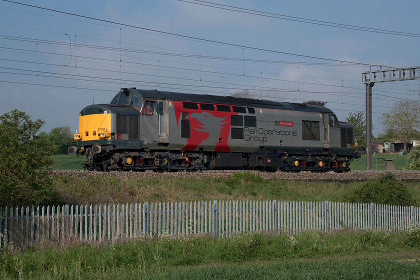 37608, 07.55 Leicester LIP-Old Oak Common (0V73, 7E), between Roade & Ashton 
 Knowing that this 07.55 Leicester LIP to Old Oak Common 0V73 working was a light engine I had in my head that it would fit in the space between a pylon and a small tree from the field just a short distance from my house with the sun also being right. I surmised correctly as 37608 'Andromeda' looks very smart passing between Roade and Ashton. The driver of the July 1961 veteran Type 3 is seen giving me the thumbs up as he opens up the engine as witnessed by the exhaust. 
 Keywords: 37608 07.55 Leicester LIP-Old Oak Common 0V73 between Roade & Ashton Andromeda Rail Operations Group UKRL