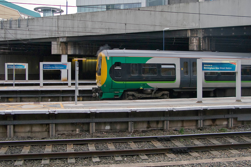 323242, LM 15.43 Longbridge-Lichfield City (2L60), Birmingham New Street station 
 323242 waits at New Street station working the 15.43 Longbridge to Lichfield City service. Notice that the driver is in the process of washing and wiping the windscreen of the train whilst waiting for the RA. 
 Keywords: 323242 15.43 Longbridge-Lichfield City 2L60 Birmingham New Street station