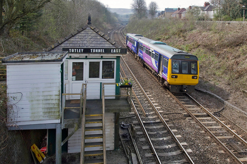 142030, NT 12.49 Manchester Piccadilly-Sheffield (2S30), Totley 
 With the Pennines in view on the skyline, 142030 is seen passing Totley Tunnel East signal box. The Pacer is working the 12.49 Manchester Piccadilly to Sheffield that will arrive at its destination in about fifteen minutes times. Notice the flower basket on the balcony of the signal box. It is the personal touches like this that are being lost as the railways 'modernise' and staff disappear away from the frontline into anonymous buildings and what are euphemistically referred to as 'signalling centres'. 
 Keywords: 142030 12.49 Manchester Piccadilly-Sheffield 2S30 Totley