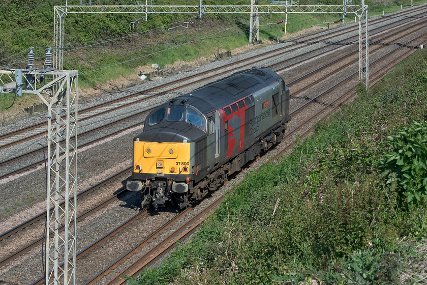 37800, 07.42 Leicester LIP-Old Oak Common (0V73, 77E), Ashton Road bridge 
 I had picked this repeat working up on RTT and noticed that it was running early again. A quick nip across the field from home finds 37800 'Cassiopeia' running light engine as the 07.42 Leicester to Old Oak Common. The locomotive is seen approaching Ashton Road bridge just south of the village of Roade. Rail Operations Group sent 37800 south to collect a Class 442 from Eastleigh the following day. 
 Keywords: 37800 07.42 Leicester LIP-Old Oak Common 0V73 Ashton Road bridge Cassiopeia ROG Rail Operations Group Pheonix